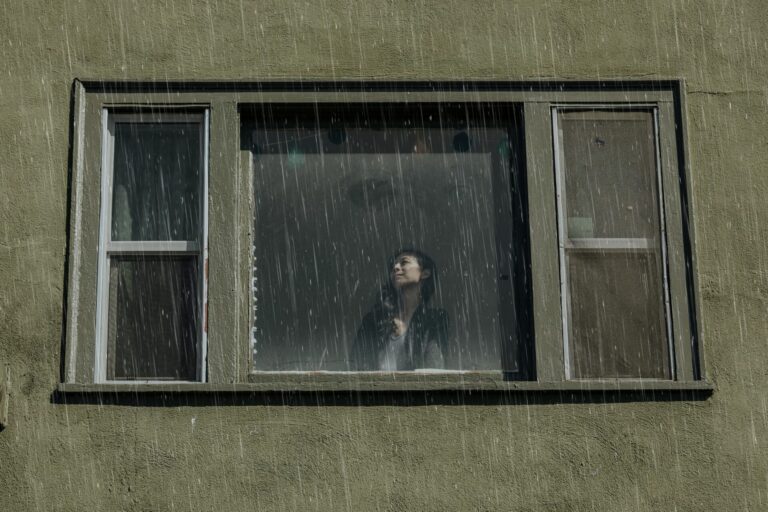 Personne à une fenêtre qui regarde la pluie