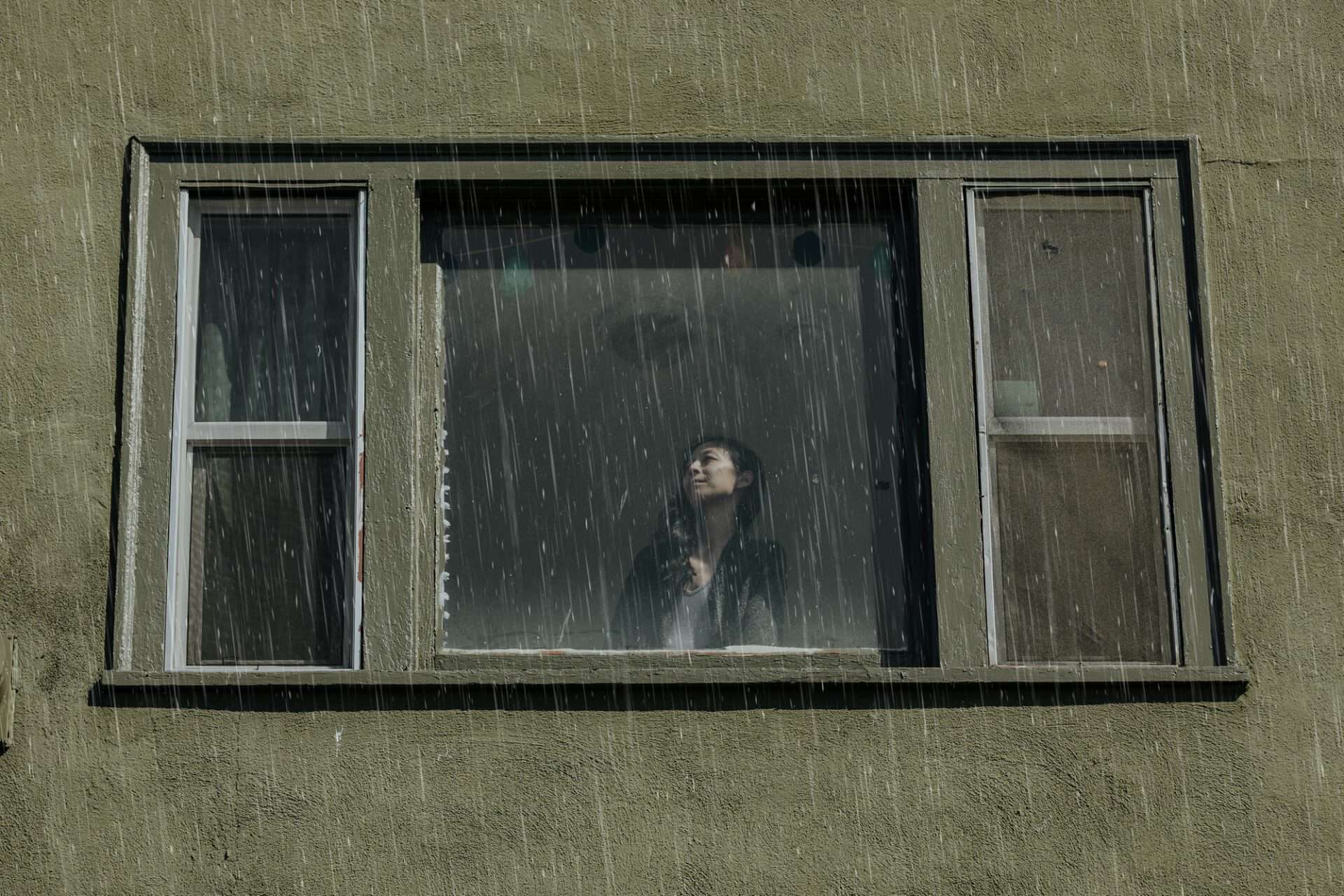 Personne à une fenêtre qui regarde la pluie