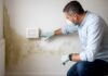 Homme installant un assécheur mural sur un mur humide et moisi